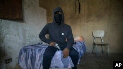 A masked gangster who goes by the nickname "El Negrito" poses for a portrait with his gun inside his gang's safe-house in the Petare slum of Caracas, Venezuela, Monday, May 13, 2019. The 24-year-old, who says he’s lost track of his murder count, is quick 