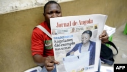 An Angolan newspaper street seller holds up a copy of the national paper in the street of Luanda, September 1, 2012. 
