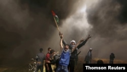 FILE - Palestinian demonstrators shout during clashes with Israeli troops at a protest demanding the right to return to their homeland, at the Israel-Gaza border east of Gaza City, April 6, 2018.