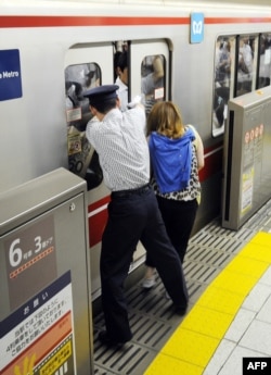 Seorang petugas membantu penumpang yang tasnya terjepit pintu kereta sementara sebuah KRL bersiap berangkat dari Stasiun Ikebukuro di Tokyo, Jepang, 12 Juli 2013.