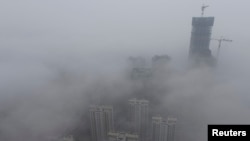 FILE - Buildings are seen shrouded in heavy haze at Qingdao development zone, Shandong province, February 25, 2014.