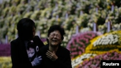 A mourner cries while assisted by an usher as she pays tribute to victims of sunken passenger ship Sewol, at the official memorial altar for the victims in Ansan, April 29, 2014.