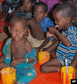 Newly arrived Somali refugee children receive their first hot meal of cereal at a feeding center run by Save the Children USA at the Dollo Ado refugee reception station, Ethiopia, October 26, 2011