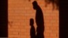 FILE - The shadows of a man and child are cast on a wall in Davie, Florida, Oct. 9, 2020. The proposed pandemic relief bill includes federal payments to families that the Center on Poverty and Social Policy said would cut the child poverty in half. 