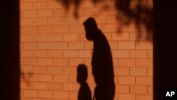 FILE - The shadows of a man and child are cast on a wall in Davie, Fla., Oct. 9, 2020. The proposed pandemic relief bill includes federal payments to families that the Center on Poverty and Social Policy said would cut the child poverty in half. 