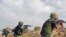This frame grab from video provided Nov. 8, 2017, by the government-controlled Syrian Central Military Media, shows Syrian pro-government troops taking up positions and firing on militants' positions on the Iraq-Syria border. 