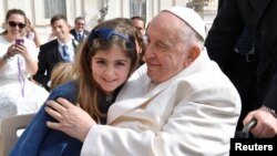 El papa Francisco abraza a una niña durante una audiencia general en la Plaza de San Pedro del Vaticano el miércoles, 29 de marzo de 2023.