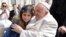 El papa Francisco abraza a una niña durante una audiencia general en la Plaza de San Pedro del Vaticano el miércoles, 29 de marzo de 2023.