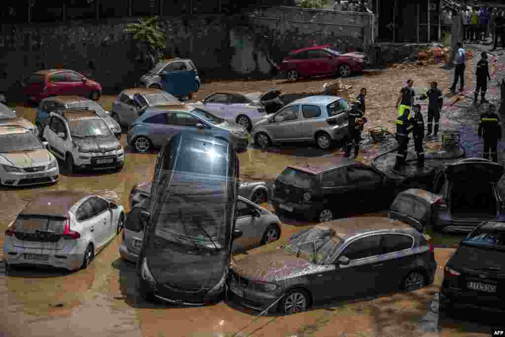 This general view shows emergency workers among damaged vehicles in a open parking area of northern Athens on July 26, 2018, after a flash flood struck the Greek capital.