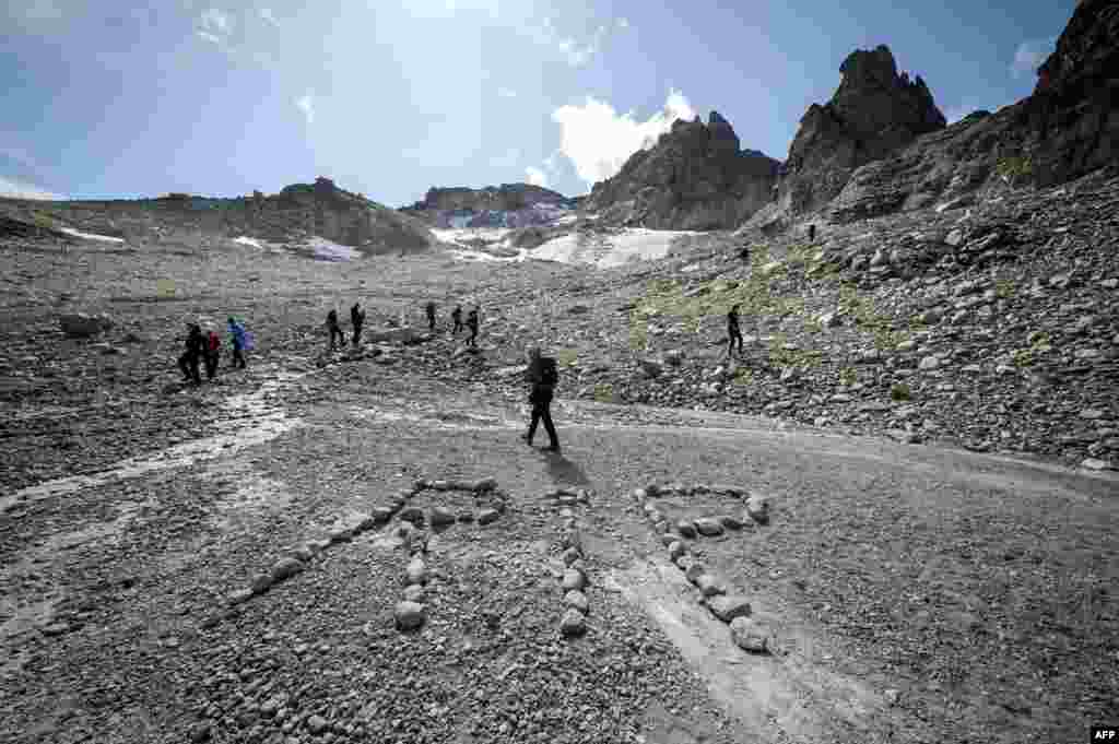 People take part in a ceremony to mark the &#39;death&#39; of the Pizol glacier (Pizolgletscher) above Mels, eastern Switzerland. In a study earlier this year, researchers of ETH technical university in Zurich determined that more than 90 percent of Alpine glaciers will disappear by 2100 if greenhouse gas emissions are left unchecked.