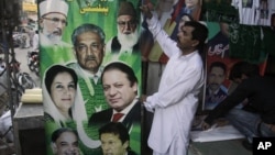 Pakistani vendors fix posters of candidates taking part in the upcoming parliamentary elections in Lahore, Pakistan, April 5, 2013.