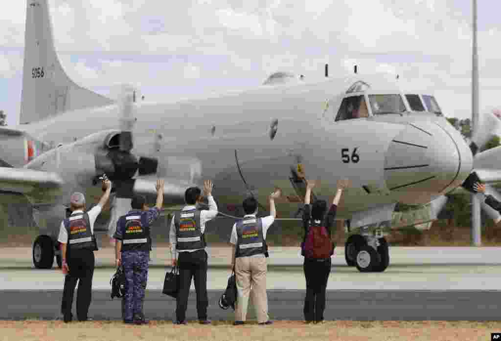 Anggota tim penyelamat Jepang melambaikan tangan pada pesawat Pasukan Pertahanan Diri Maritim Jepang ketika bersiap untuk mencari pesawat penerbangan MH370, di Pangkalan Udara Militer Australia Pearce di Perth, 24 Maret 2014.