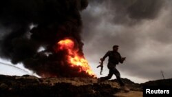 FILE - Flames and smoke rise from oil wells set ablaze by Islamic State militants before they fled the oil-producing region of Qayyara, Iraq, Nov. 4, 2016.