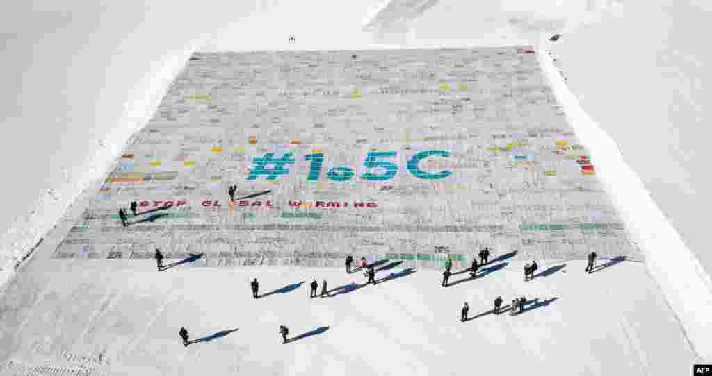 An aerial view of a massive collage of 125,000 drawings and messages from children from around the world about climate change is seen rolled out on the Aletsch Glacier at an altitude of 3,400 meters near the Jungfraujoch in the Swiss Alps, smashing the world record for the giant postcard.