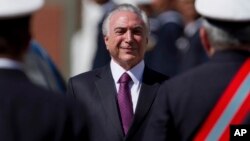 FILE - Brazil's President Michel Temer smiles as he receives military honors during a ceremony, in Brasilia, June 9, 2017.