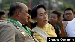 Aung San Suu Kyi (d) conversa con el general Zaw Win (i), viceministro de Asuntos Fronterizos, durante el desfile por el Día de las Fuerzas Armadas en Birmania. 