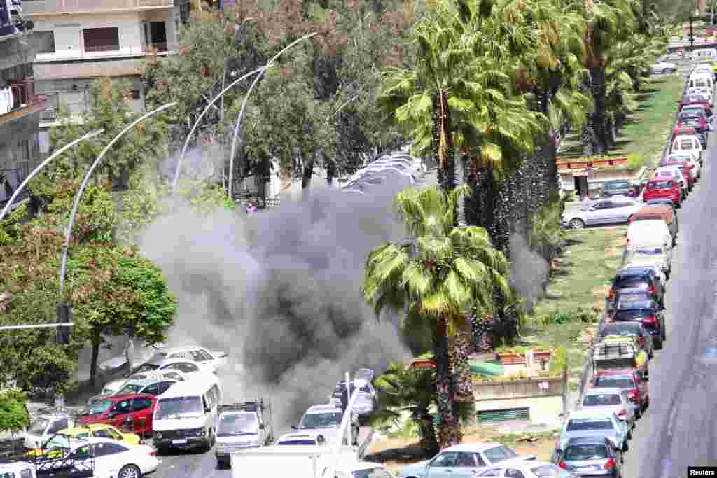 Smoke rises after mortar bombs landed on the Kafr Sousa area in Damascus in this handout distributed by Syria&#39;s national news agency SANA. One woman was killed and thirteen people were injured, SANA said. 