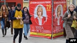 Warga Rusia berjalan melewati banner kampanye di Moskow (foto: dok). 