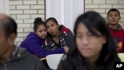 FILE - Central American migrants embrace as they wait for assistance at a center for newly-arrived migrant families with children, at Sacred Heart Catholic Church in McAllen, Texas. Assistance includes clothes, a meal, a shower and access to medical care, Jan. 5, 2016.