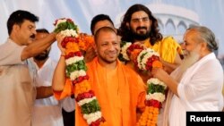 FILE - Supporters of Yogi Adityanath (C), Chief Minister of India's most populous state of Uttar Pradesh, present him with a garland on the occasion of the birthday celebration of Nritya Gopal Das, a famous Hindu priest, in Ayodhya, India, May 31, 2017. 
