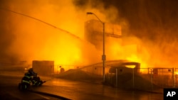 Firefighters battle a blaze, after rioters plunged part of Baltimore into chaos, torching a pharmacy, setting police cars ablaze and throwing bricks at officers, April 27, 2015.