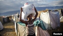 Seorang perempuan di Cite Soleil, Port-au-Prince di Haiti, memanggul karung berisi beras yang dibagikan lembaga bantuan AS, USAID. (Foto: Dok)
