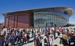 FILE - Guests stand outside the new Spaceport America hangar in Upham, N.M., Oct. 17, 2011. Operators of the New Mexico Spaceport Authority that runs Spaceport America are seeking greater confidentiality for tenants that include aspiring commercial spaceflight company Virgin Galactic.