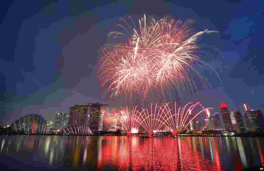 Fireworks explode above Singapore&#39;s financial skyline at dusk as part of celebrations for the nation&#39;s 50th year of independence.