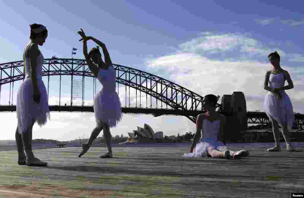 Ballerinas from the Australian Ballet perform on a floating platform during a promotional event in front of the Sydney Opera House and Harbour Bridge.