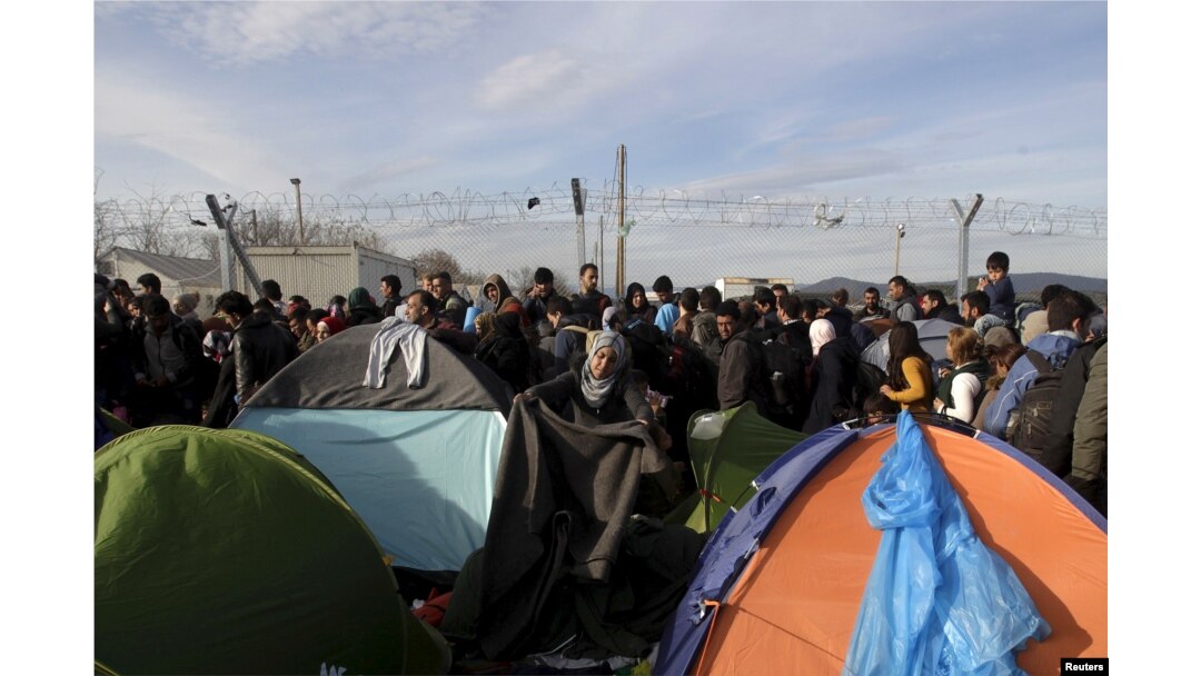 A migrant arranges a blanket among tents at a makeshift camp for refugees and migrants at the Greek-Macedonian border, near the village of Idomeni, Greece, March 5, 2016.