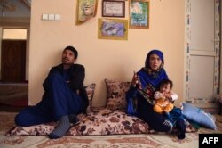 Afghan mother Jahantab Ahmadi, right, 25, holds her youngest child during an interview with AFP as her husband Musa Mohammadi, 27, looks on at a house in Kabul, March 24, 2018.