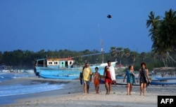 FILE - Foreign tourists walk along a beach in Sri Lanka's seafront eastern town of Trincomalee on July 7, 2010.