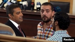ນັກຂ່າວໂທລະພາບ Al Jazeera Mohamed Fahmy, ຊ້າຍ, ແລະ Baher Mohamed, ທີສອງຈາກຊ້າຍ ລົມກັນກ່ອນການຟັງຄຳພິພາກສາທີ່ສານໃນນະຄອນຫຼວງ Cairo, ອີຈິບ. 29 ສິງຫາ, 2015. 