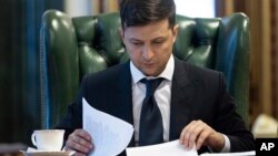 FILE - Ukrainian President Volodymyr Zelenskiy looks at documents at his office in Kyiv, Ukraine, May 20, 2019.