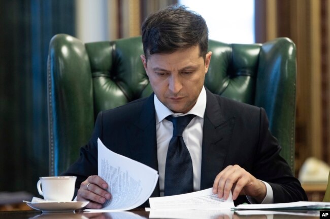 FILE - Ukrainian President Volodymyr Zelenskiy looks at documents at his office in Kyiv, Ukraine, May 20, 2019.