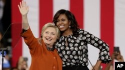 Democratic presidential candidate Hillary Clinton, accompanied by first lady Michelle Obama, greet supporters during a campaign rally in Winston-Salem, N.C., Oct. 27, 2016. Researcher Susan Madsen says there are striking similarities among powerful women across the globe.