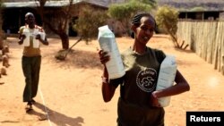 Keepers carry bottles of milk before feeding orphaned elephants, at the Reteti elephant sanctuary in Samburu county, Kenya, October 15, 2021. (REUTERS/Baz Ratner)