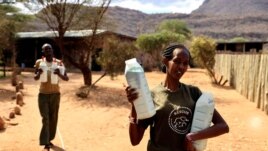 Keepers carry bottles of milk before feeding orphaned elephants, at the Reteti elephant sanctuary in Samburu county, Kenya, October 15, 2021. (REUTERS/Baz Ratner)