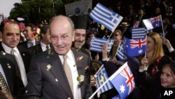 FILE - Then-President of Greece Constantine Stephanopoulos is greeted by school children, waving Greek and Australian flags and throwing flower petals, as he arrives at the Greek Orthodox Archdiocese in Sydney, Australia, June 7, 2002.