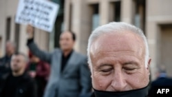 Seorang pengunjuk rasa berdiri di luar gedung pengadilan di Istanbul sambil menutup mulutnya dengan kain hitam, saat berlangsungnya sidang Can Dundar, pemimpin redaksi surat kabar oposisi Cumhuriyet, dan kepala bironya di Ankara, Erdem Gul, 1 April 2016 (Foto: dok).