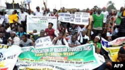 FILE - Students and workers carry placards as they sit on the Lagos-Ikorodu highway to protest against the suspension of academic activities following a nationwide strike by lecturers in state-owned universities, Aug. 13, 2013 in Lagos. 