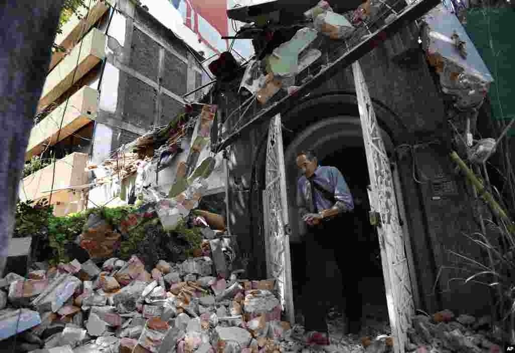 A man walks out of the door frame of a collapsed building after an earthquake, in the Condesa neighborhood of Mexico City, Sept. 19, 2017.