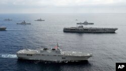 In this photo taken Nov. 16, 2012 and released by U.S. Navy, the USS George Washington aircraft carrier, second row from bottom right, and JS Hyuga, bottom, cruise with other ships from the U.S. Navy and the Japan Maritime Self-Defense Force in East China Sea.