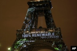 FILE- Artwork entitled 'One Heart One Tree' by artist Naziha Mestaoui is displayed on the Eiffel tower ahead of the 2015 Paris Climate Conference, in Paris. The Paris Agreement on climate change cams into force Nov. 4, 2016, after a year with remarkable success in international efforts to slash man-made emissions of carbon dioxide and other global warming gases.