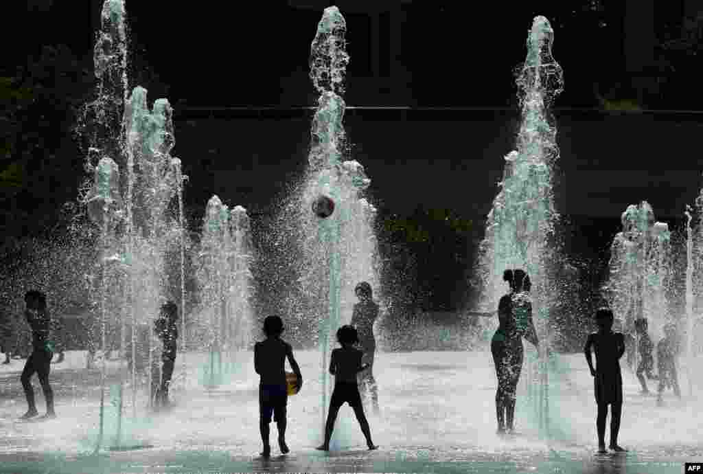 Children are playing with water jets at the Parc Andre Citroen in Paris.
