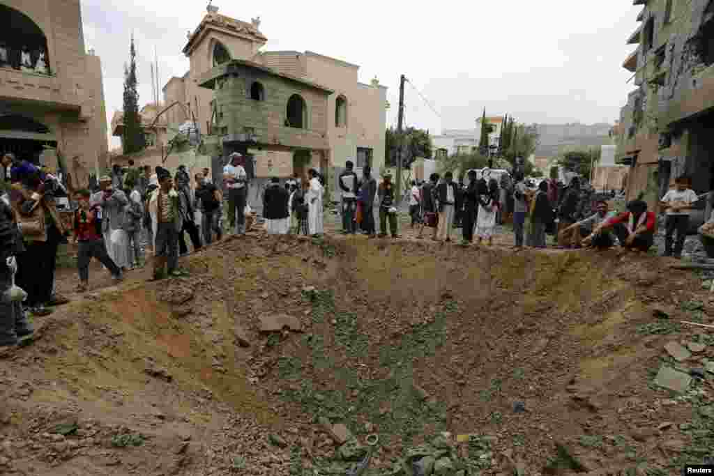 People stand around a crater at the site of a Saudi-led airstrike in Yemen&#39;s capital Sana&#39;a.