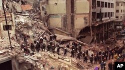 Lính cứu hỏa và nhân viên cứu hộ tìm kiếm trong đống đổ nát của trung tâm cộng đồng của người Do Thái sau vụ đánh bom hồi năm 1994.