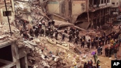 FILE - In this July 18, 1994 file photo, firefighters and rescue workers search through the rubble of the Argentine-Israeli Mutual Association community center, after a car bomb rocked the building in downtown Buenos Aires, Argentina.