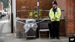 A British police officer guards a cordon around a plastic covered trash bin near John Baker House for homeless people in Salisbury, England, July 5, 2018.