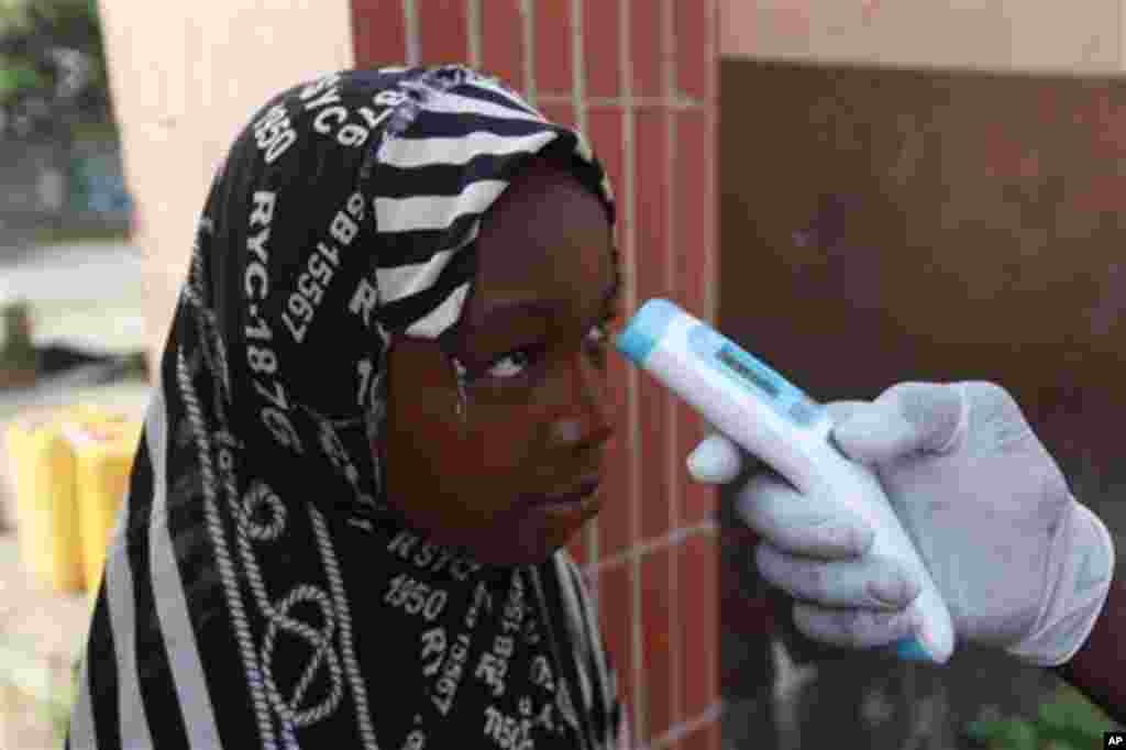 Seorang guru menggunakan termometer untuk menguji suhu murid-muridnya, untuk memeriksa kemungkinan gejala Ebola di SD Adekunle di Lagos, Nigeria (8/10).&nbsp;(AP/Sunday Alamba) 